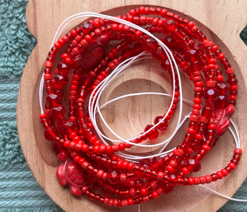 Red waist bead with turtles on it